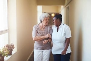 assisted living facility resident walking down hall with care taker